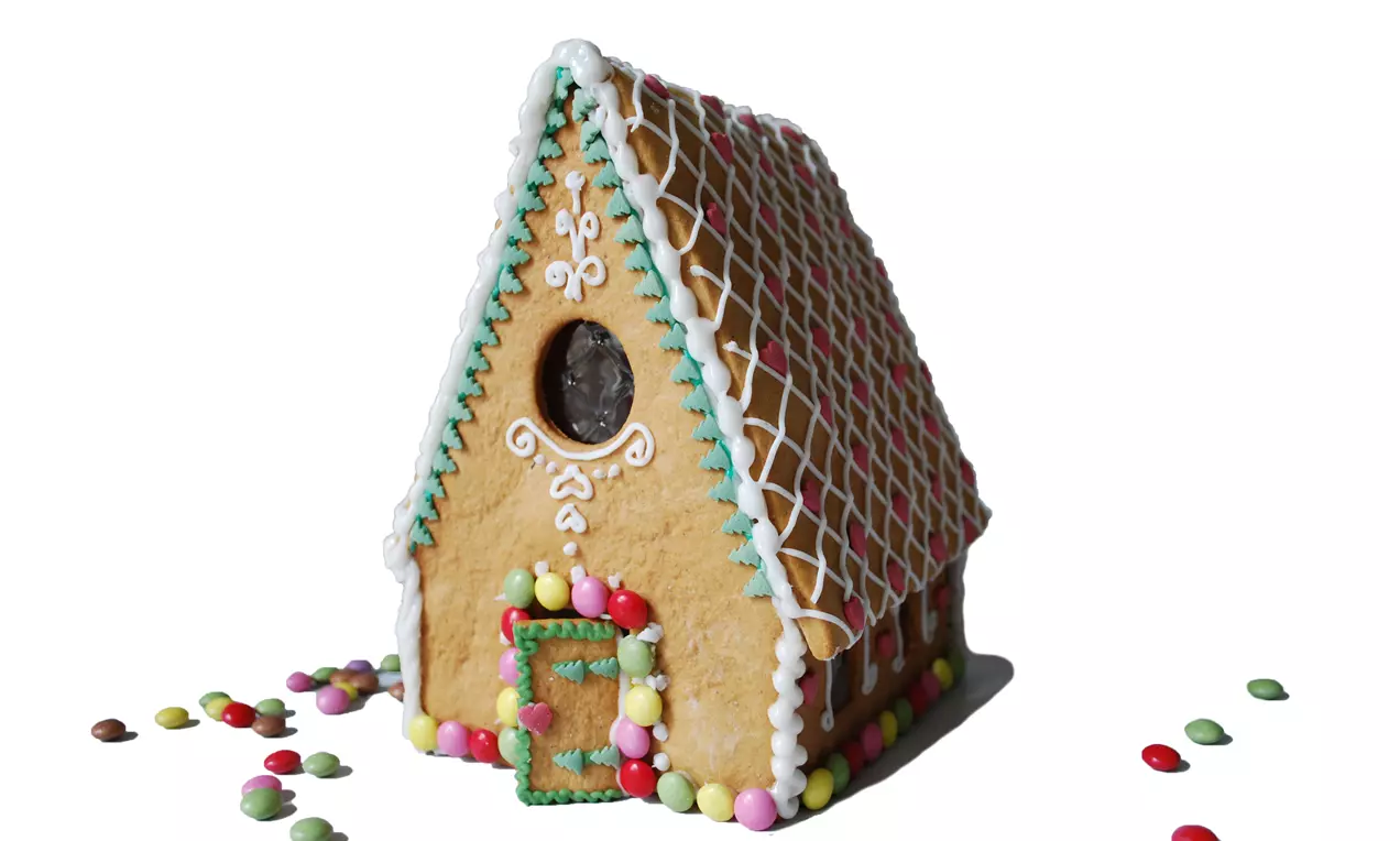 Färgglatt pepparkakshus med vit glasyr, mönstrat tak, runda fönster och spritsade detaljer, dekorerat med färgglada godisbitar